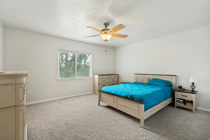 Carpeted room featuring a ceiling fan with integrated lighting, a window with horizontal blinds, and neutral wall tones
