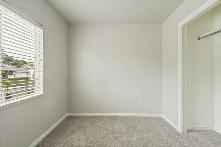 Neutral-toned interior room featuring light gray walls, gray carpeting, and white baseboards