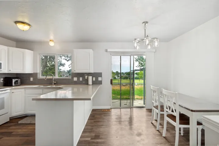 Bright kitchen and dining area featuring white cabinetry, light countertops, and wood-finish flooring
