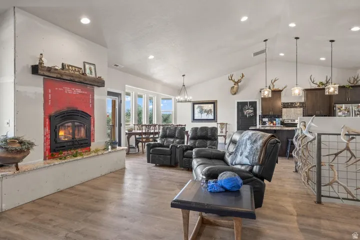 Living area featuring a prominent fireplace with a substantial wood mantel, vaulted ceilings, and recessed lighting