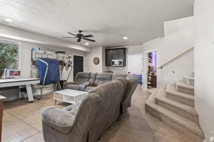 Spacious entertainment room featuring recessed lighting, a ceiling fan, a window, and wood-finish flooring