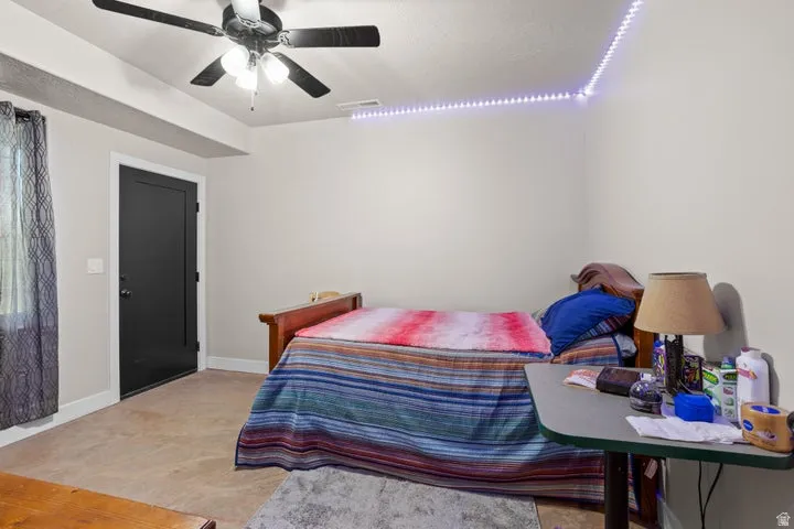 Spacious room featuring a dark panel door, neutral wall paint, and a ceiling fan with integrated lighting