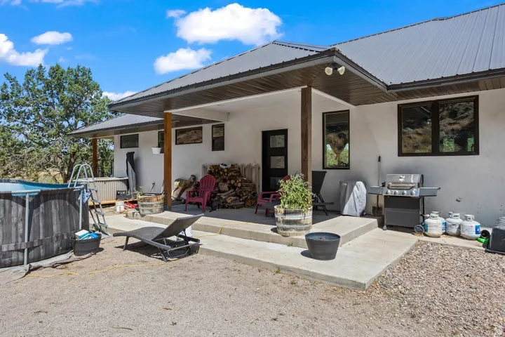 Exterior patio area featuring a metal roof, white stucco siding, and dark-framed windows
