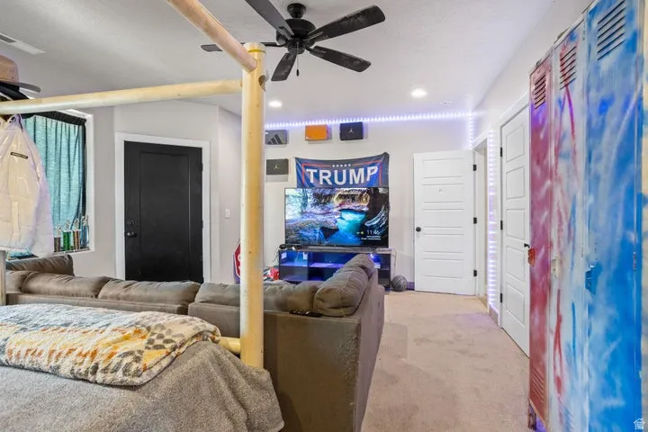 Carpeted room featuring a ceiling fan, recessed lighting, and a black paneled door