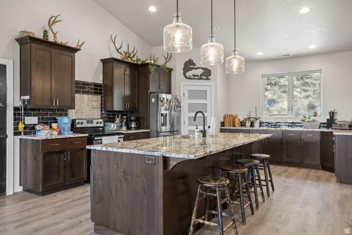Open-concept kitchen featuring an oversized island with a granite countertop and pendant lighting