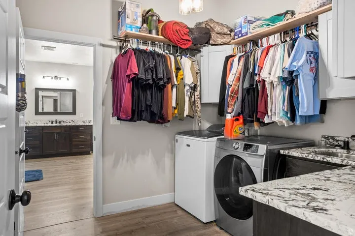 Laundry area featuring wood-finish flooring, built-in shelving, and a sink with a stone-finish countertop