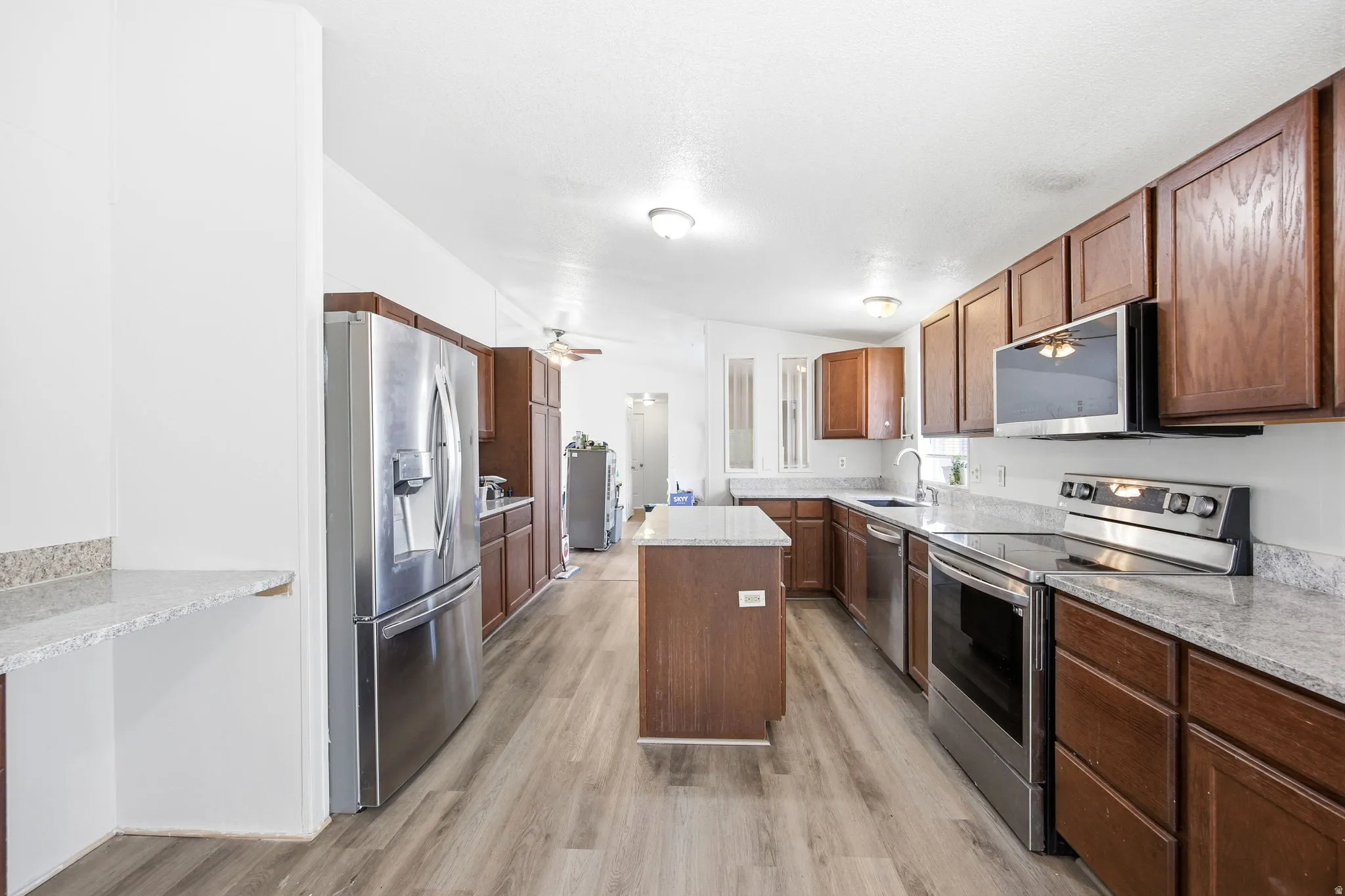 Kitchen featuring wood-finish flooring, a central island, and abundant wood cabinetry