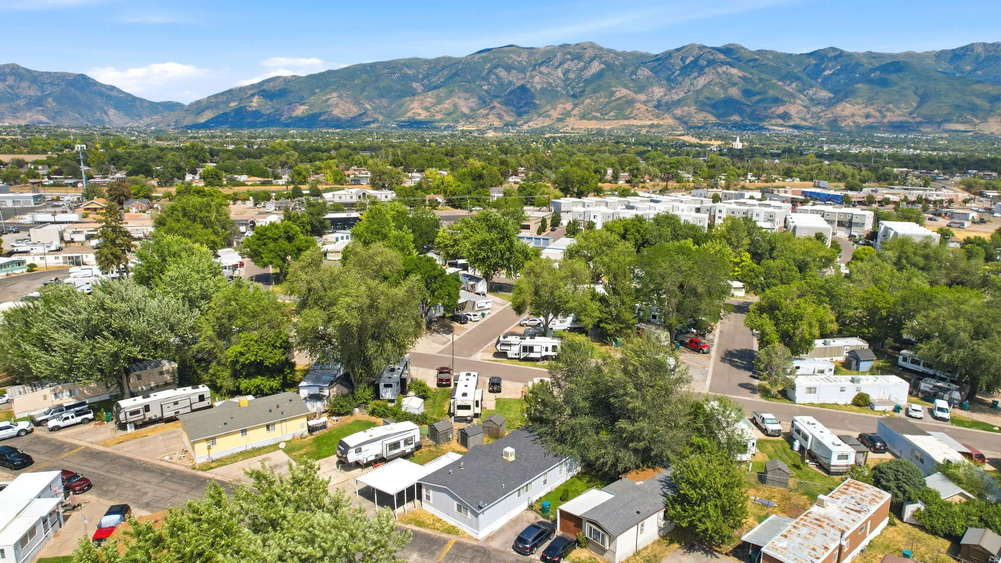 Expansive property featuring multiple manufactured homes and RV parking, all surrounded by mature trees