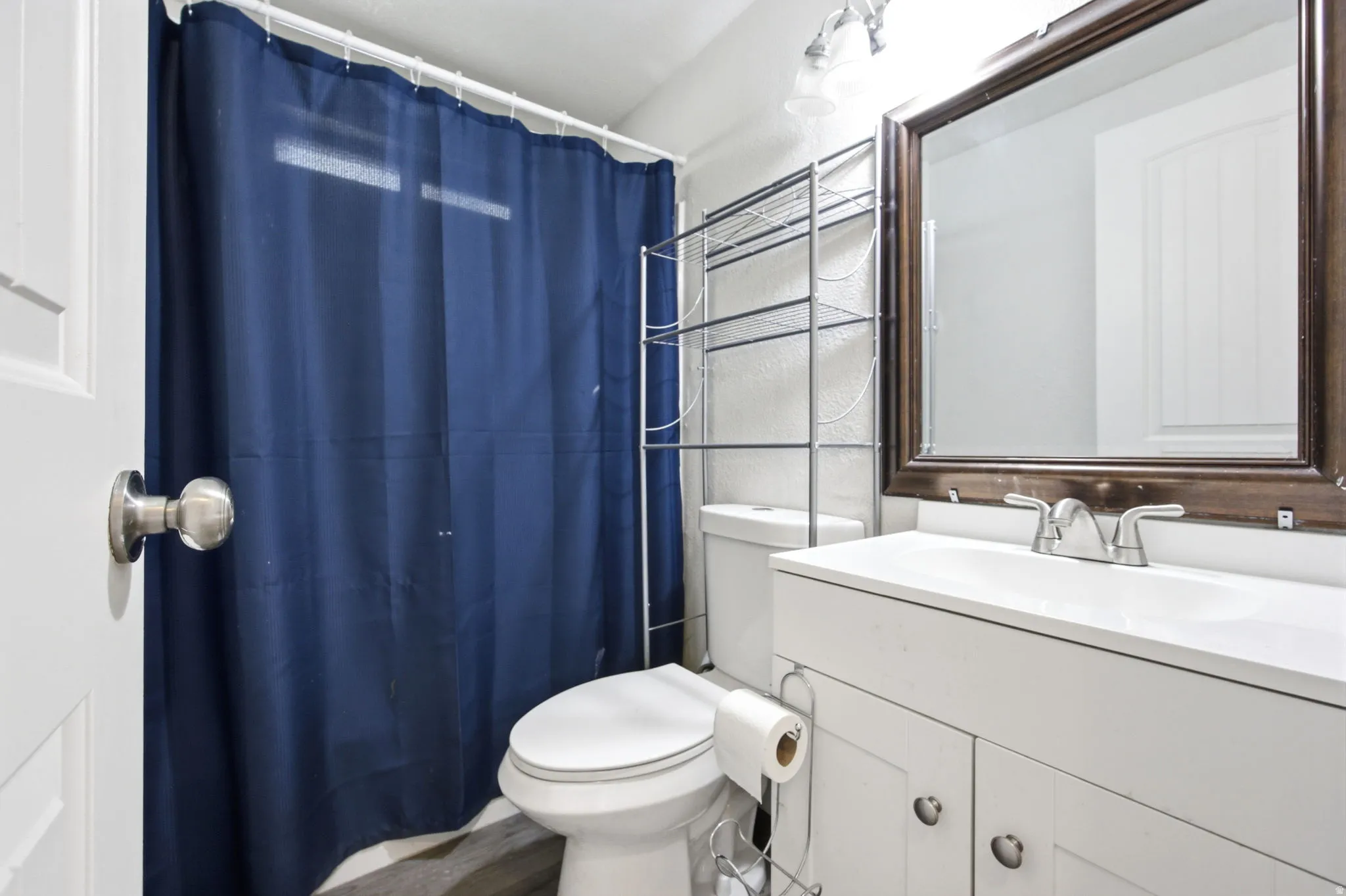 Bathroom with a white vanity featuring a single basin sink, brushed nickel faucet, and white cabinetry