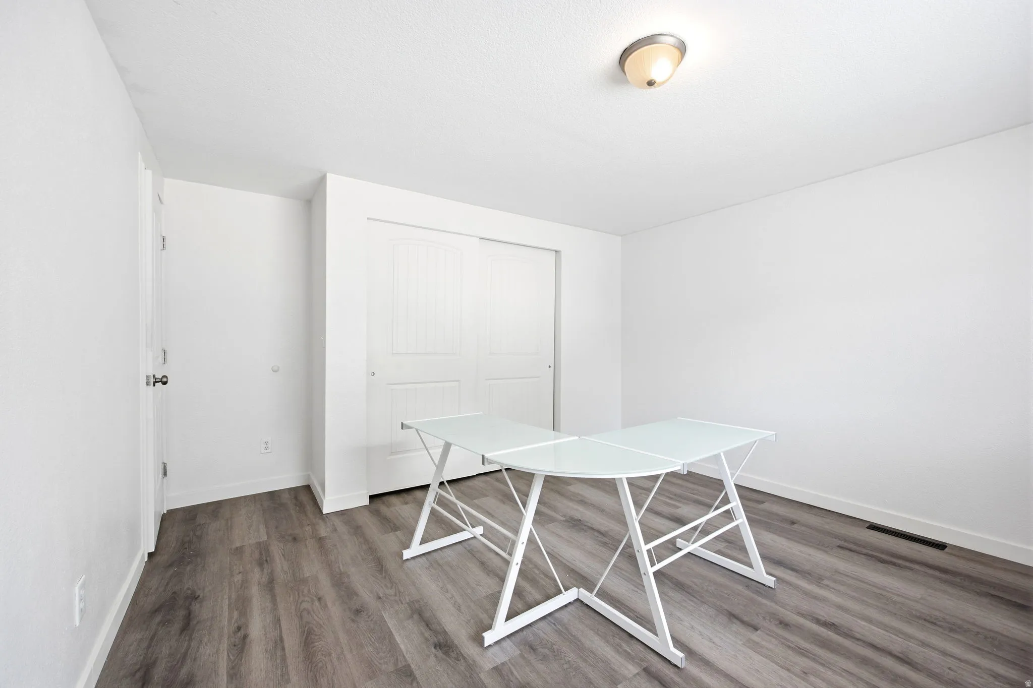 Room featuring wood-finish flooring, white walls, and a ceiling-mounted light fixture
