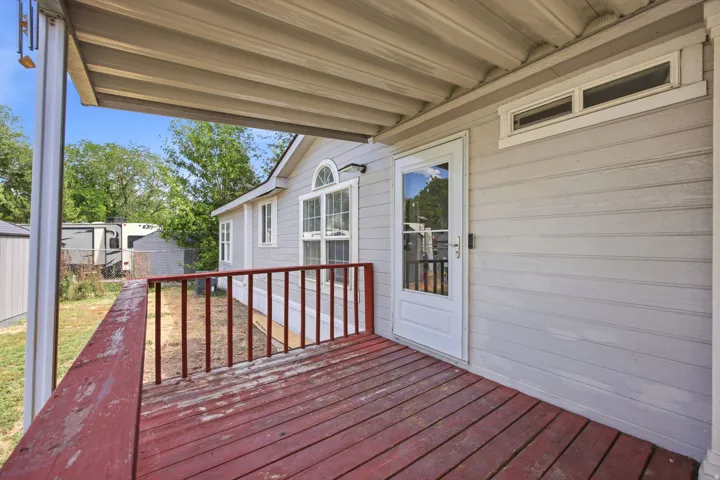 Covered porch featuring wood flooring and red railings