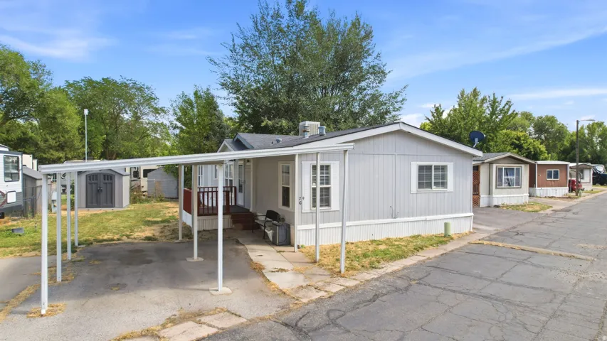 Manufactured home featuring light gray siding, white trim, and a dark shingled roof