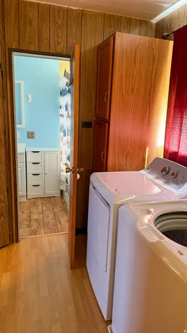 Laundry area featuring wood-finish flooring, wood paneling, and an integrated storage cabinet