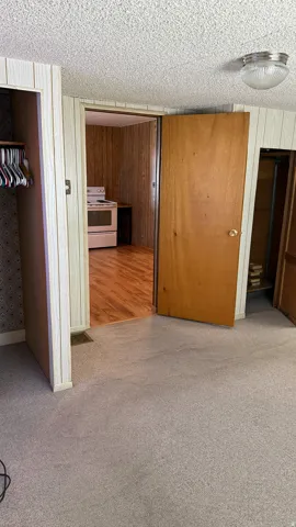 Carpeted interior space with a wood-finish door and white textured ceiling