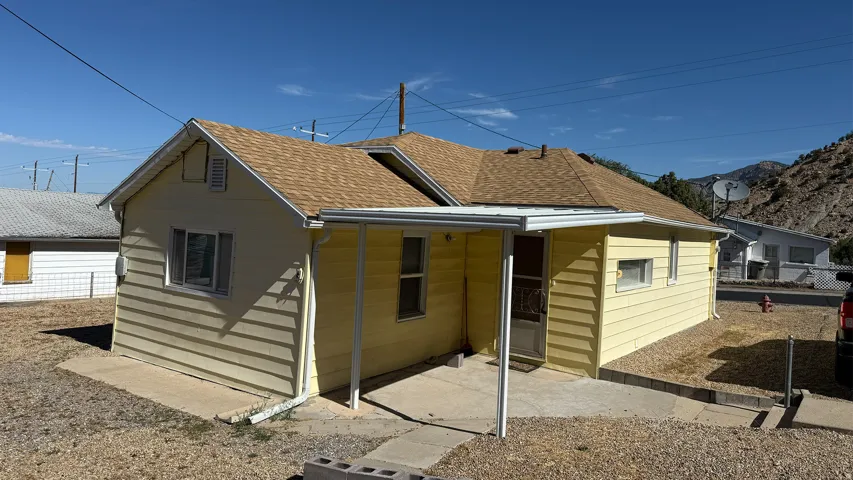 Yellow siding exterior with a brown shingle roof