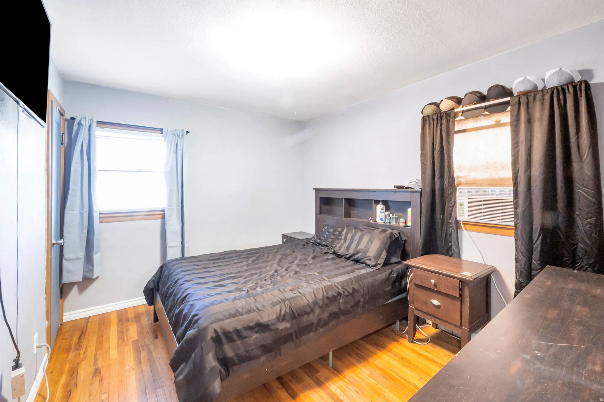 Wood-finish flooring throughout, two windows with wood trim, and a ceiling-mounted light fixture