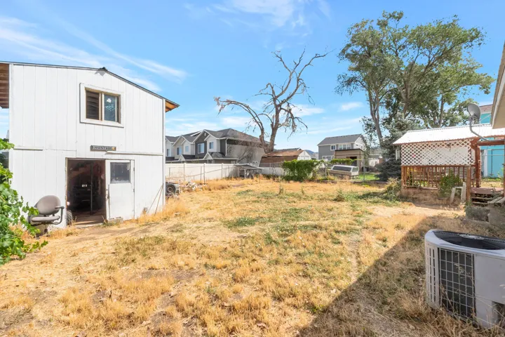 Backyard featuring a detached outbuilding, wood deck with lattice enclosure, and mature trees
