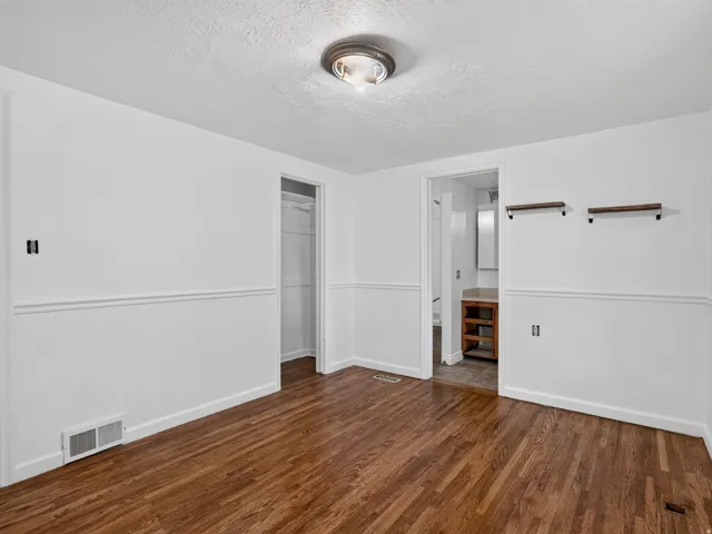 Interior room featuring wood-finish flooring, white walls with wainscoting, and a ceiling-mounted light fixture
