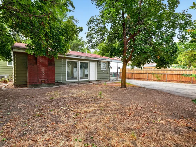 Rear exterior featuring a red brick chimney, sliding glass doors, and a partial privacy fence