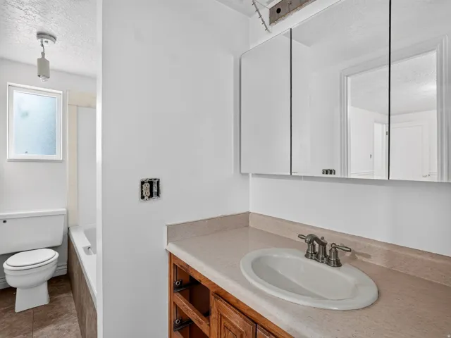 Bathroom vanity featuring an oval sink with a two-handle faucet, a light-toned countertop, and a mirrored medicine cabinet