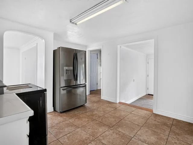 Kitchen featuring a stainless steel French door refrigerator, brown tiled flooring, and white walls