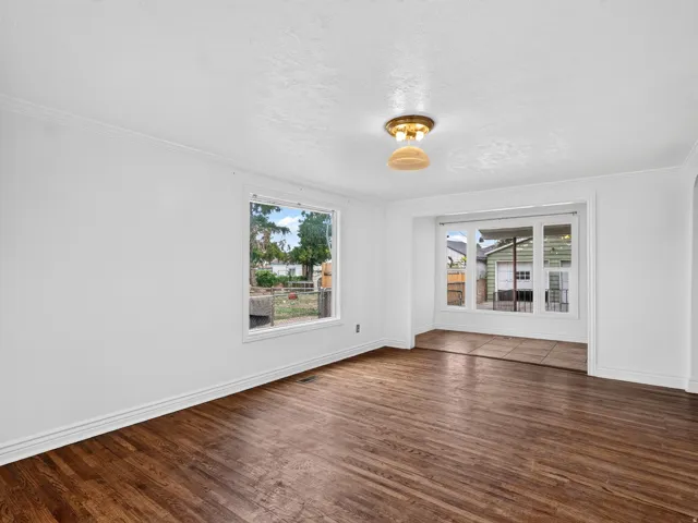 Spacious interior room featuring wood-finish flooring, white walls, and bright trim
