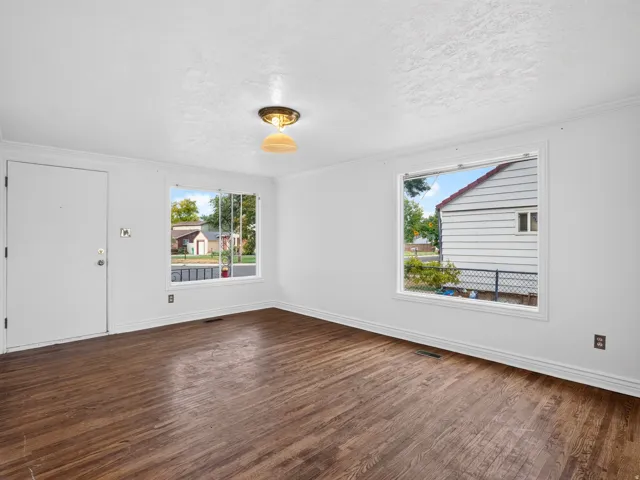 Spacious room featuring rich wood-finish flooring, crisp white walls, and bright white trim
