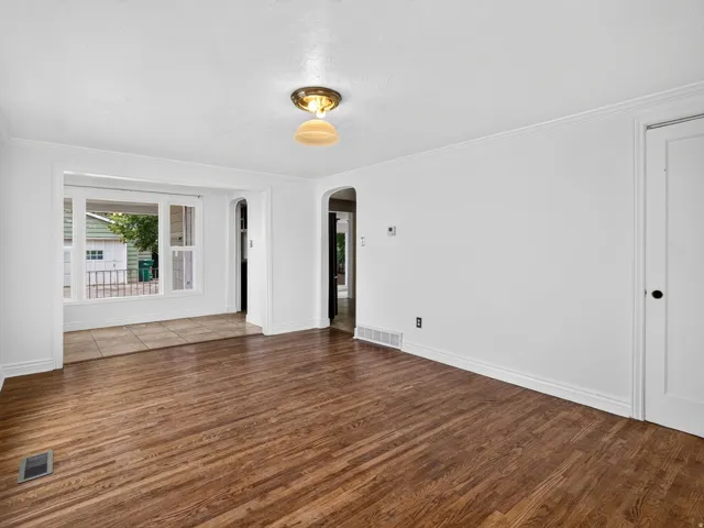 Spacious room featuring wood-finish flooring and white baseboards