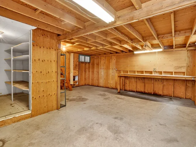 Spacious unfinished basement featuring exposed wood joists and concrete flooring
