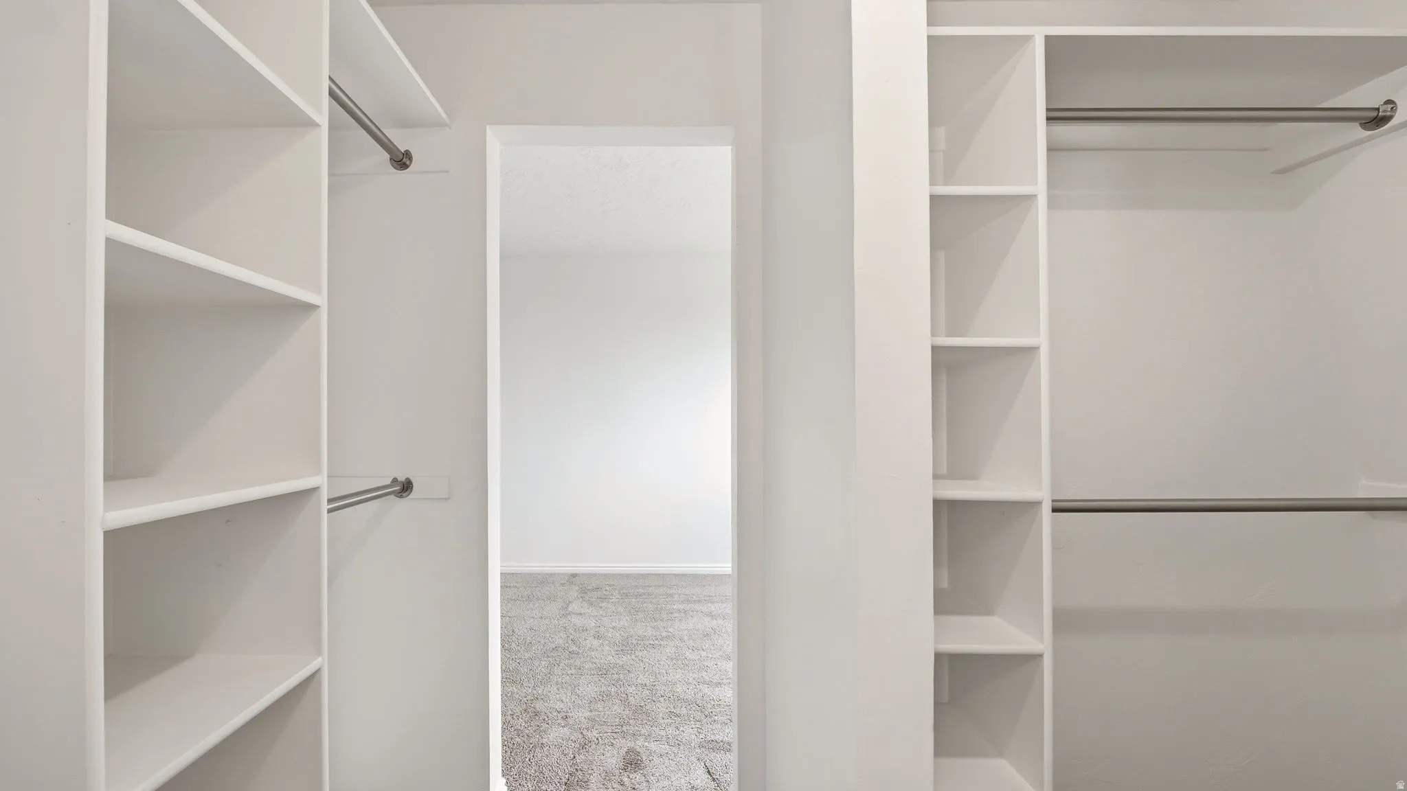 Built-in closet system featuring white shelving and chrome hanging rods