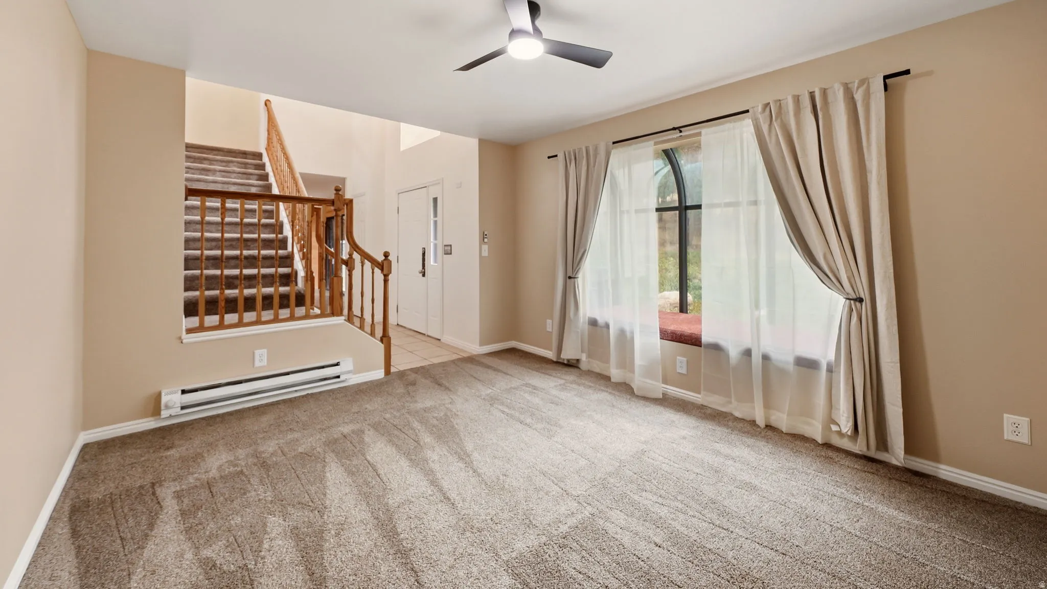 Carpeted living area with a large arched window featuring a built-in window seat