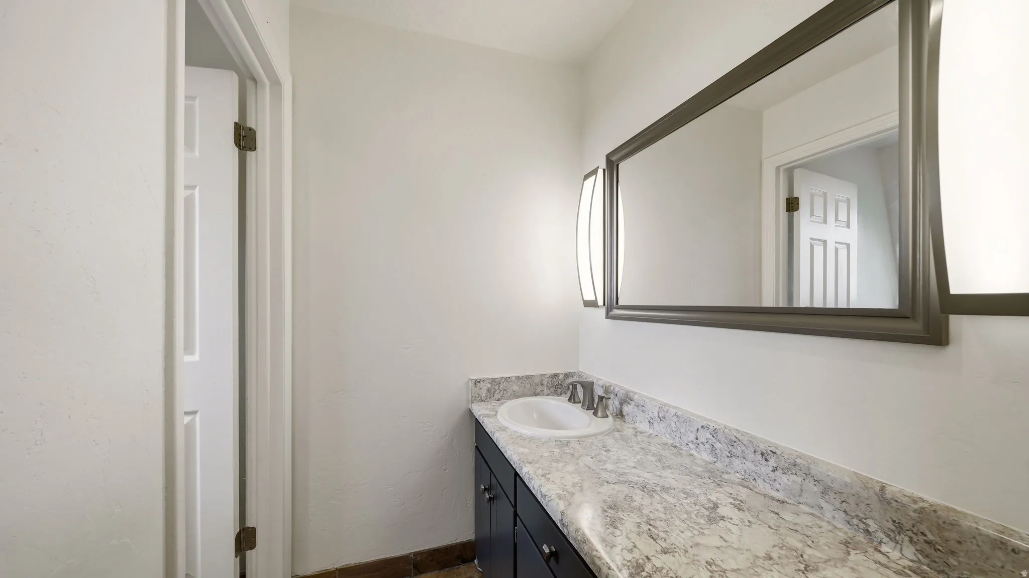 Vanity featuring a stone-look countertop, integrated sink, and dark wood cabinetry