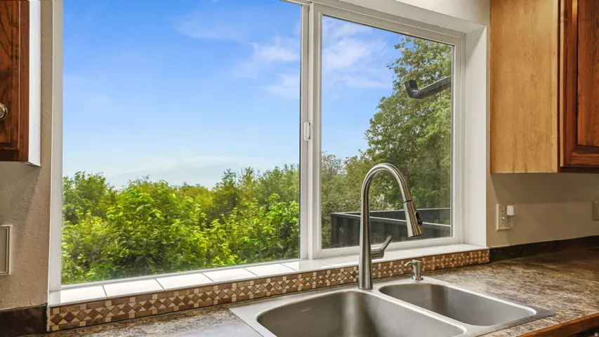 Dual basin stainless steel sink with a gooseneck faucet positioned beneath a window