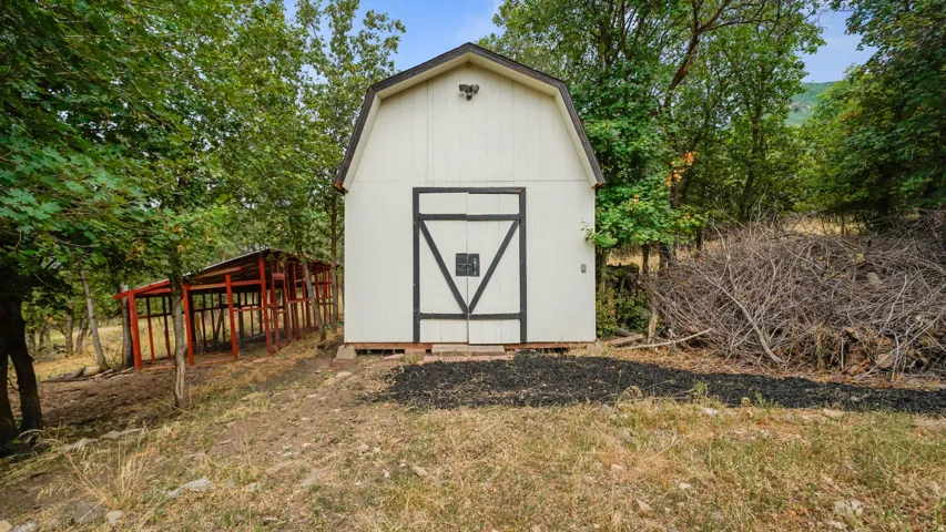 Gable-roofed shed with white siding and black barn-style doors