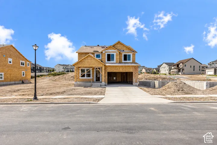New construction framing with an integrated two-car garage, concrete driveway, and concrete sidewalk