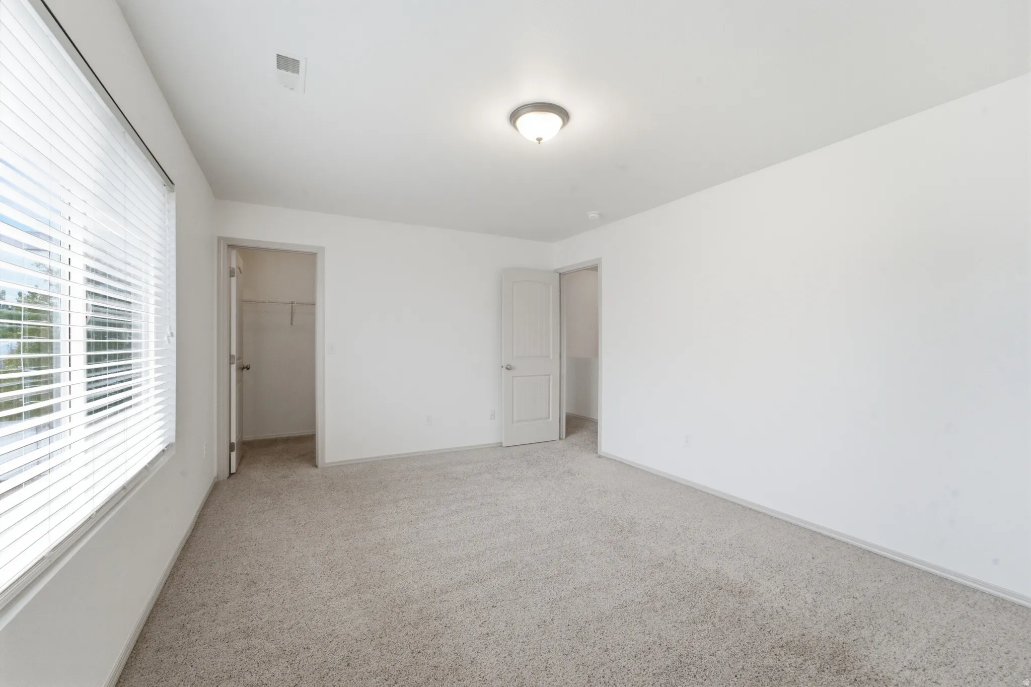 Carpeted room featuring white walls, a single window with horizontal blinds, and a flush mount ceiling light