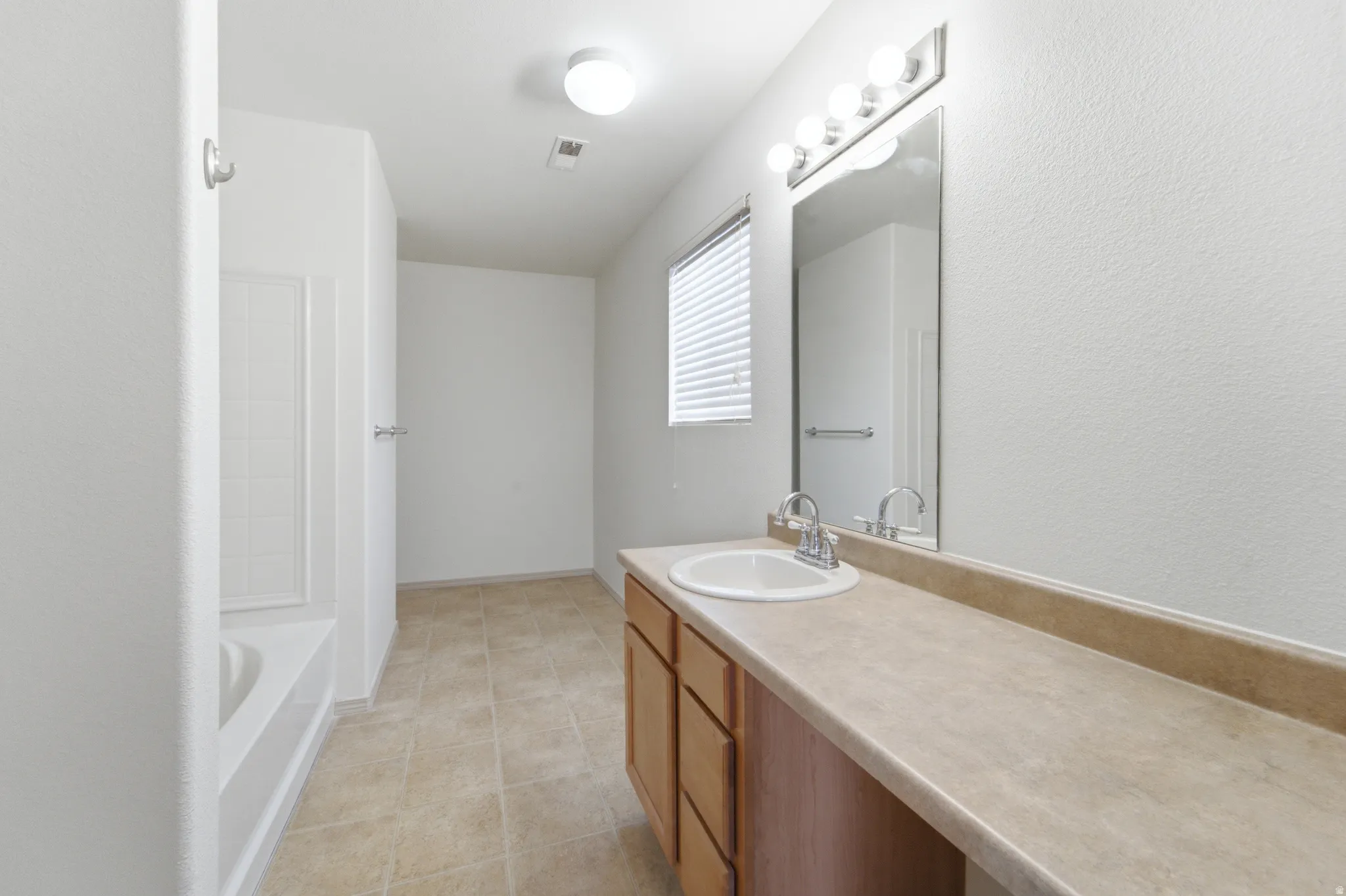Full bathroom featuring a single vanity, integrated sink, and large mirror