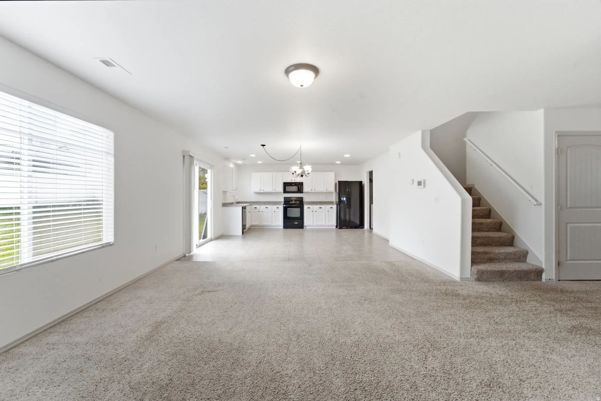 Open-concept living space with light-toned carpeting and white walls