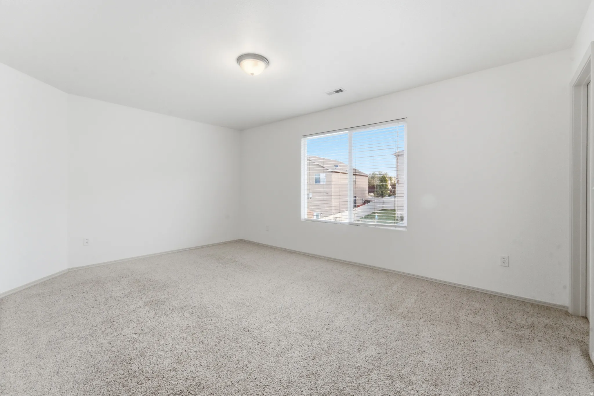 Neutral-toned carpet flooring, white painted walls, and a flush mount ceiling light fixture