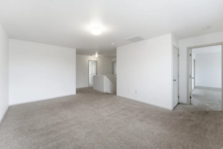 Carpeted flooring, white painted walls, flush mount lighting, interior doors, and a partial staircase