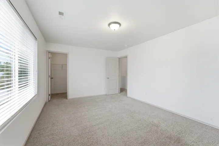 Carpeted room featuring white walls, a single window with horizontal blinds, and a flush mount ceiling light