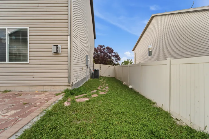 Fenced rear yard with lush lawn and brick paver patio, offering privacy and outdoor space