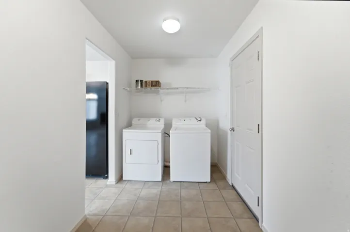 Laundry area featuring floor tiling, overhead lighting, and wire shelving