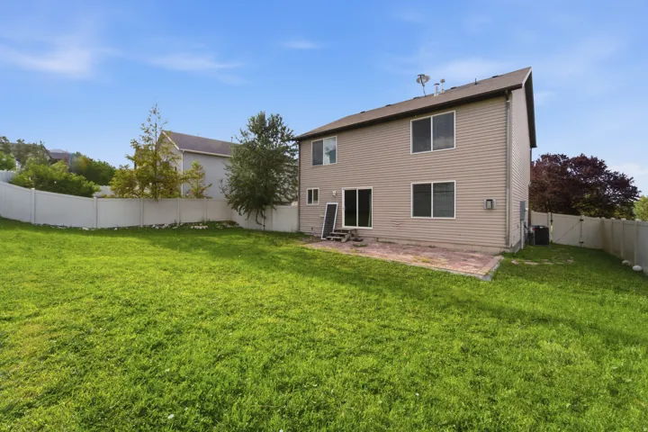 Expansive grassy yard with full vinyl fencing and a paver patio