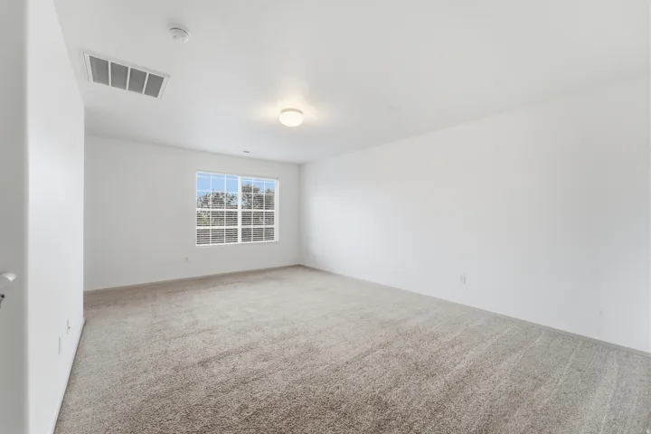 Expansive room featuring light-colored carpeting, white wall finishes, and a multi-paned window