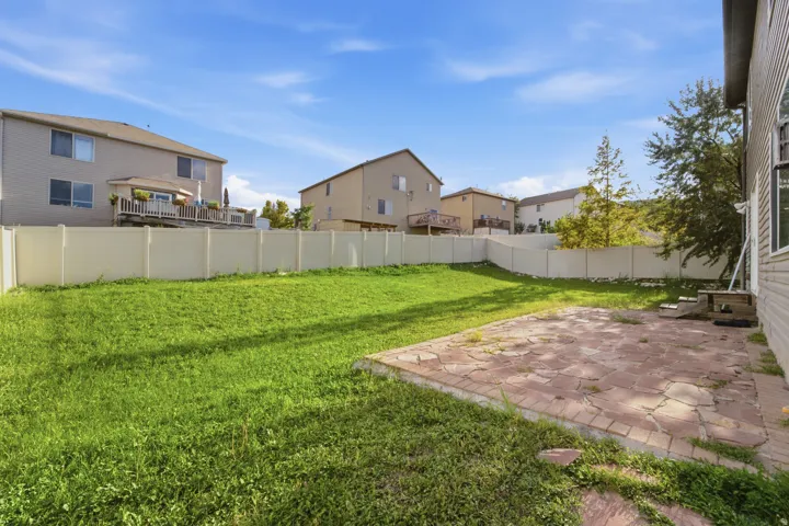 Expansive outdoor space featuring a large lawn area, a stone patio, and perimeter fencing