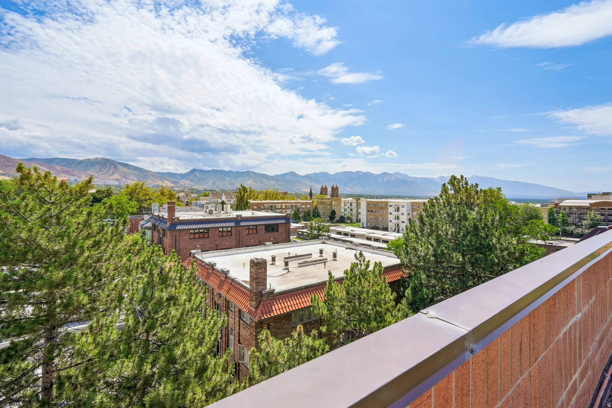 Expansive mountain backdrop with distant buildings and lush evergreen trees
