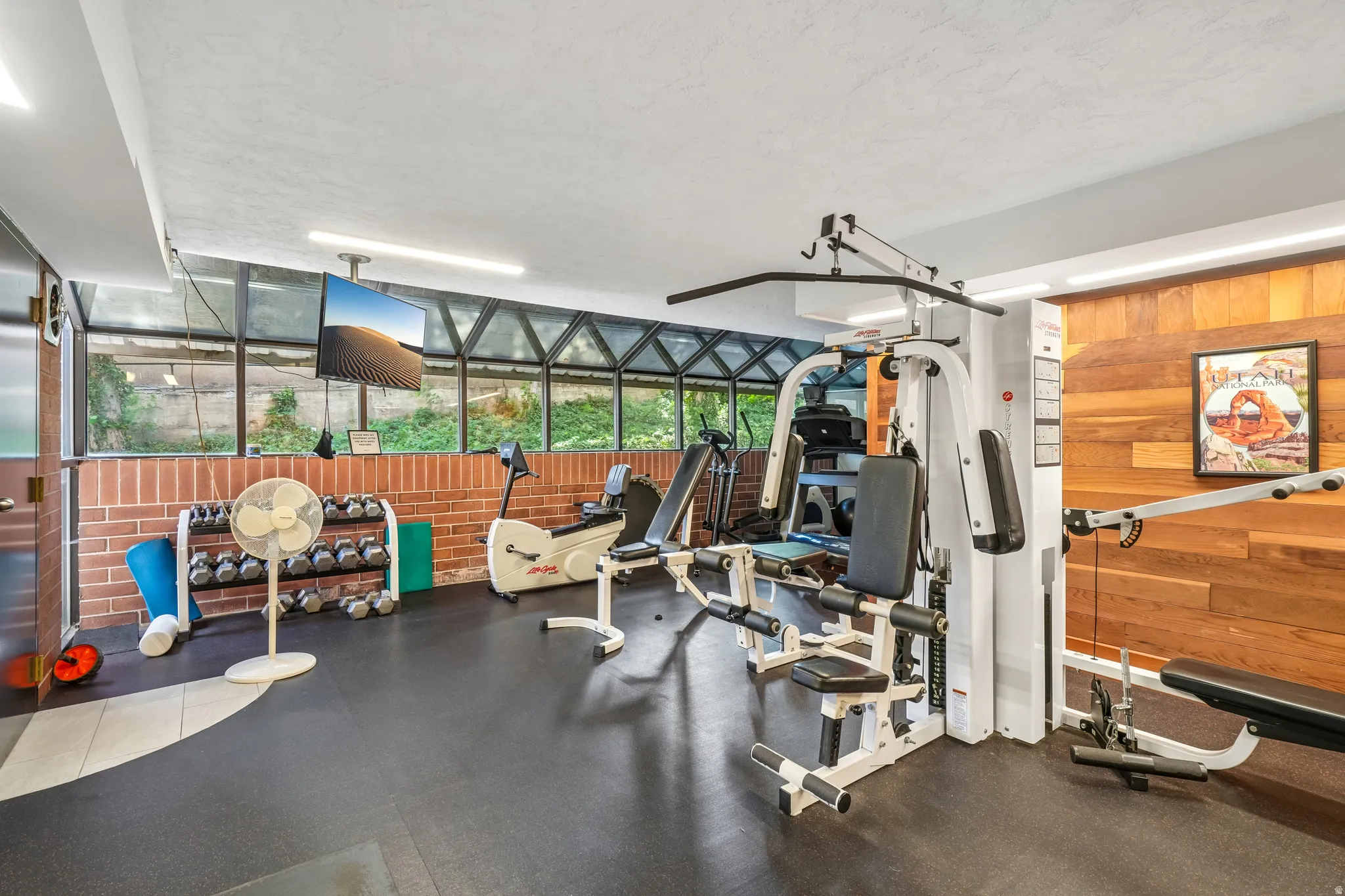 Dedicated fitness area featuring rubber flooring and wood-paneled accent wall