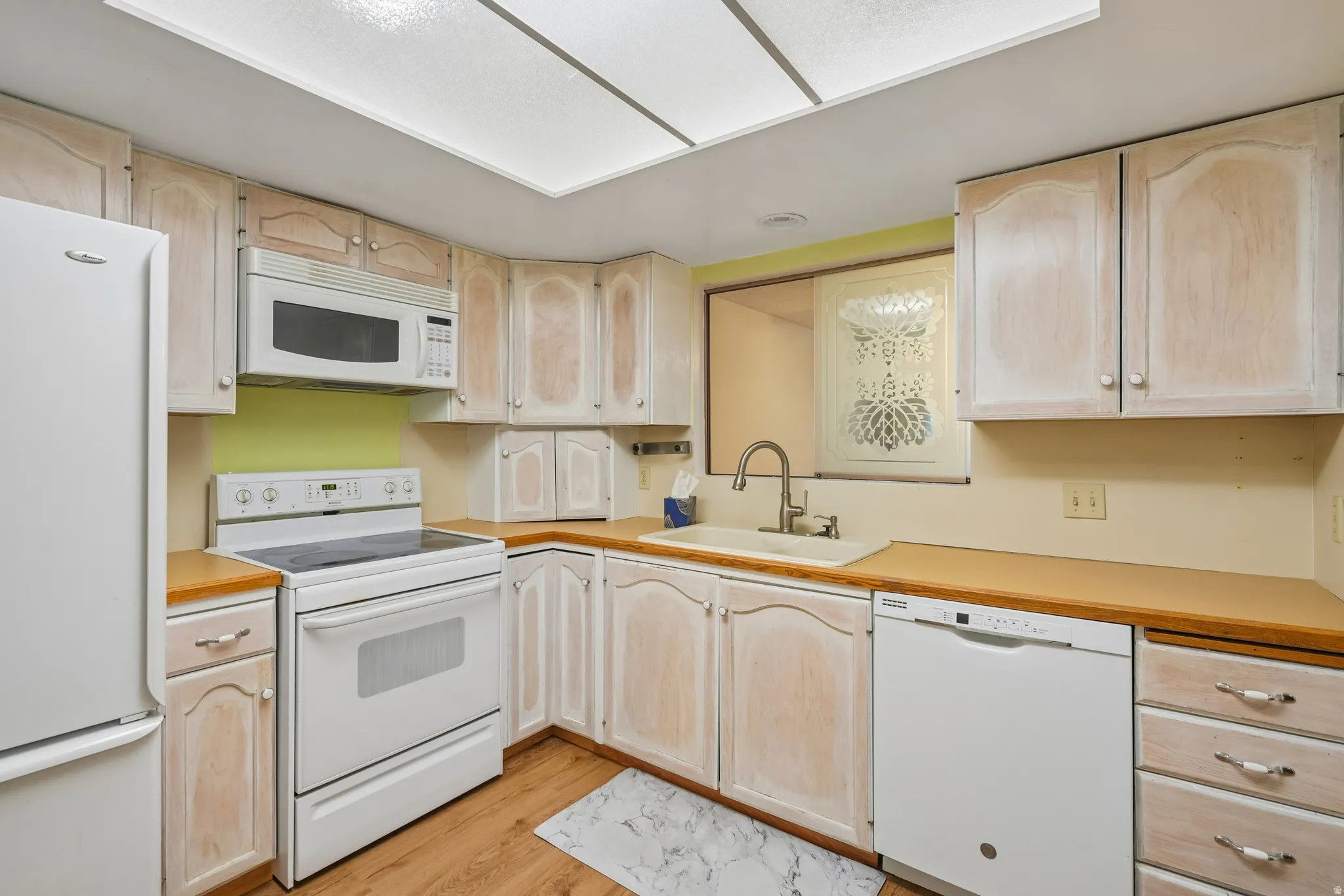 Kitchen featuring wood-finish flooring and light-toned cabinetry