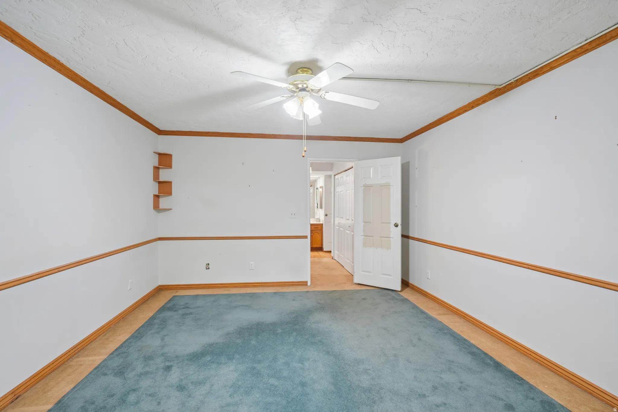 Room featuring a ceiling fan, crown molding, chair rail, built-in shelving, and a combination of carpet and wood-finish flooring